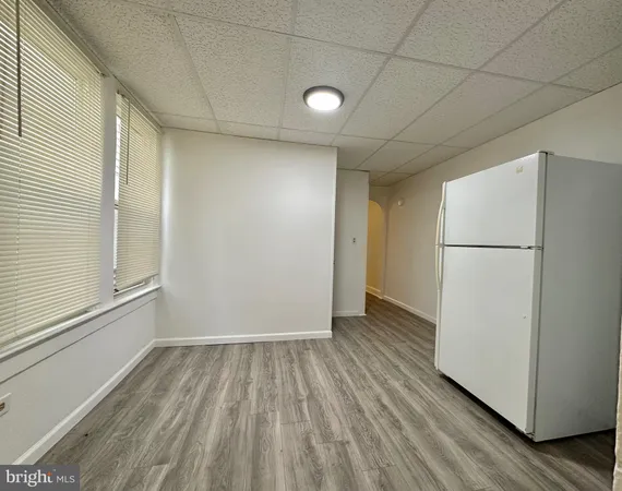 a view of a room with wooden floor and a refrigerator