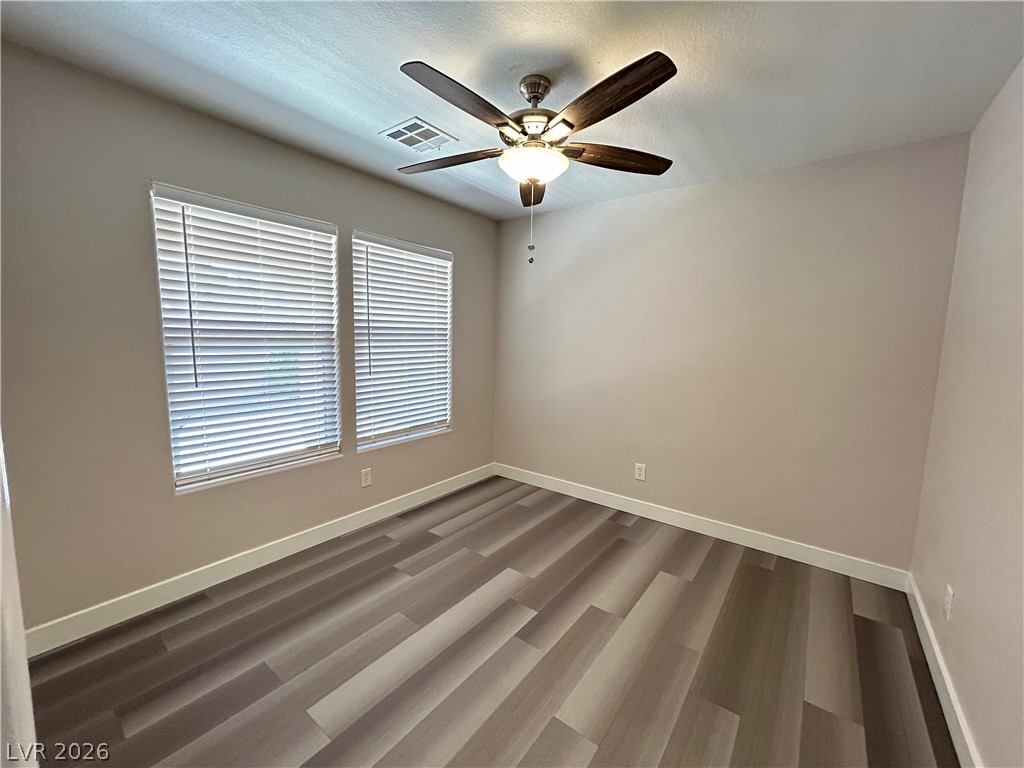 6538 Elm Spring Las Vegas, NV 89148 - Photo 16 of 29 A well-lit bedroom features durable laminate flooring and a functional ceiling fan with lighting.