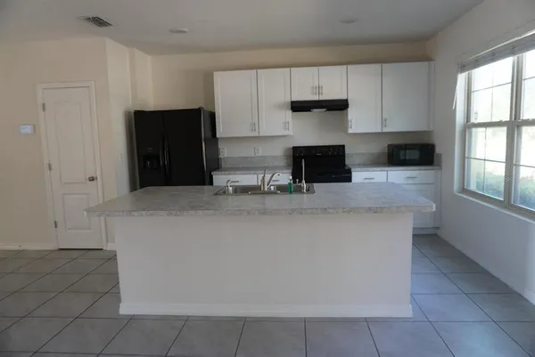 a kitchen with kitchen island a counter top space appliances and a window