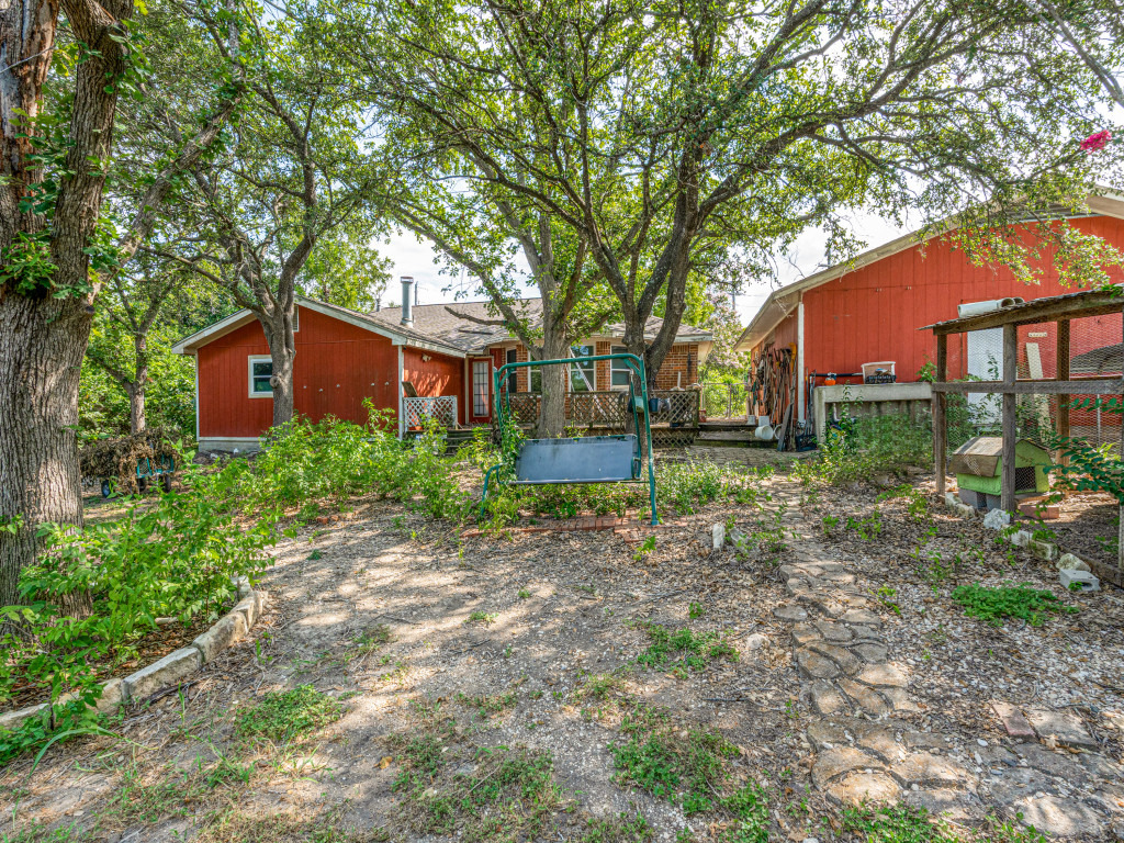 1035 Palomino Road Kyle, TX 78640 - Photo 6 of 13 A quaint residence nestled among mature trees, with a stone-lined pathway leading through the yard.