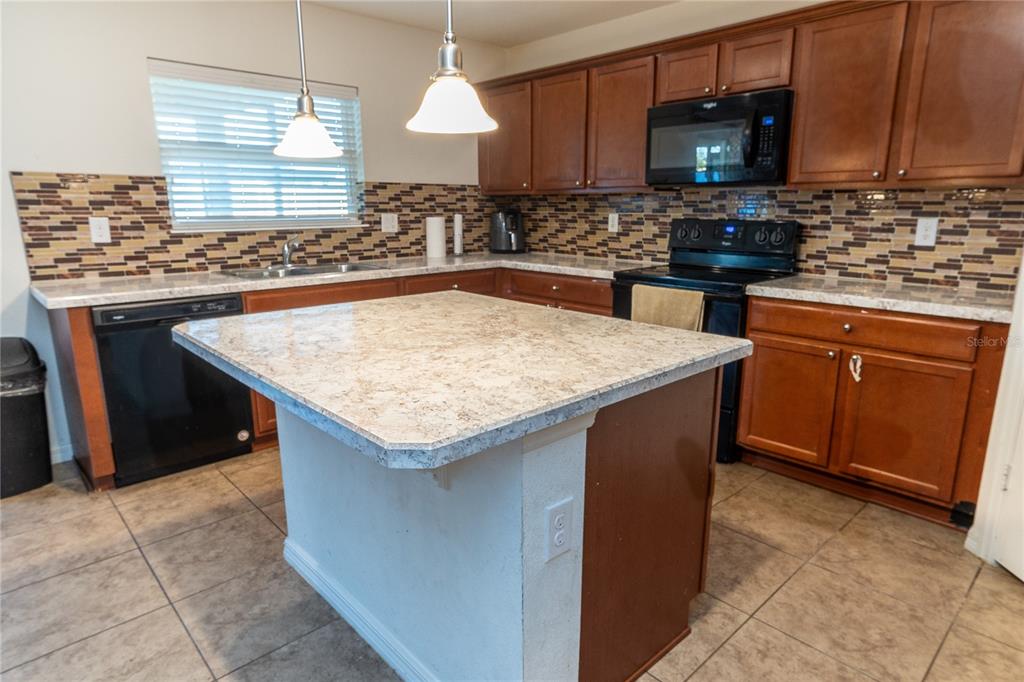 4563 Orchard Grove Road St. Cloud, FL 34772 - Photo 38 of 51 a kitchen with kitchen island granite countertop wooden cabinets a sink and a stove