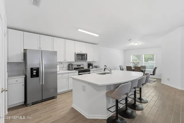 a kitchen with stainless steel appliances a sink a stove a refrigerator cabinets and wooden floor