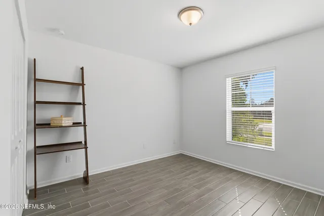a view of an empty room with a window and wooden floor