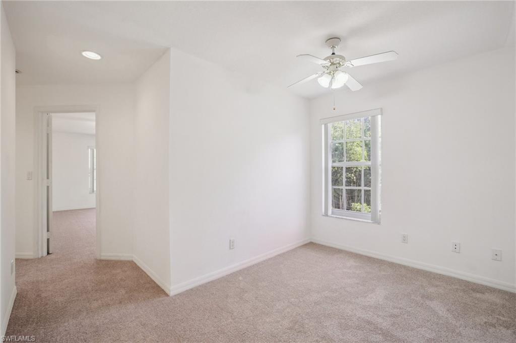 5348 Cypress Lane Naples, FL 34113 - Photo 21 of 28 an empty room with chandelier fan and windows