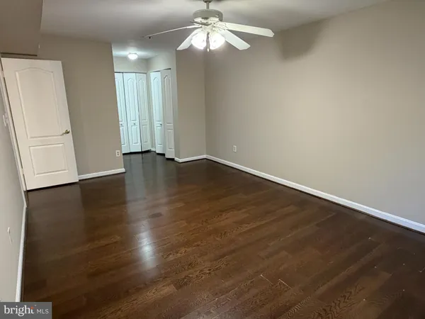 an empty room with wooden floor chandelier fan and windows