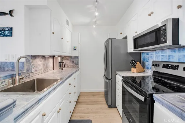a kitchen with granite countertop a sink a stove and cabinets