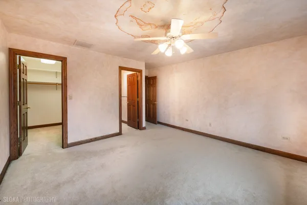 an empty room with a chandelier fan and windows