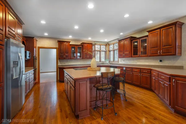 a kitchen with stainless steel appliances granite countertop wooden cabinets a refrigerator a sink a stove and a wooden floors