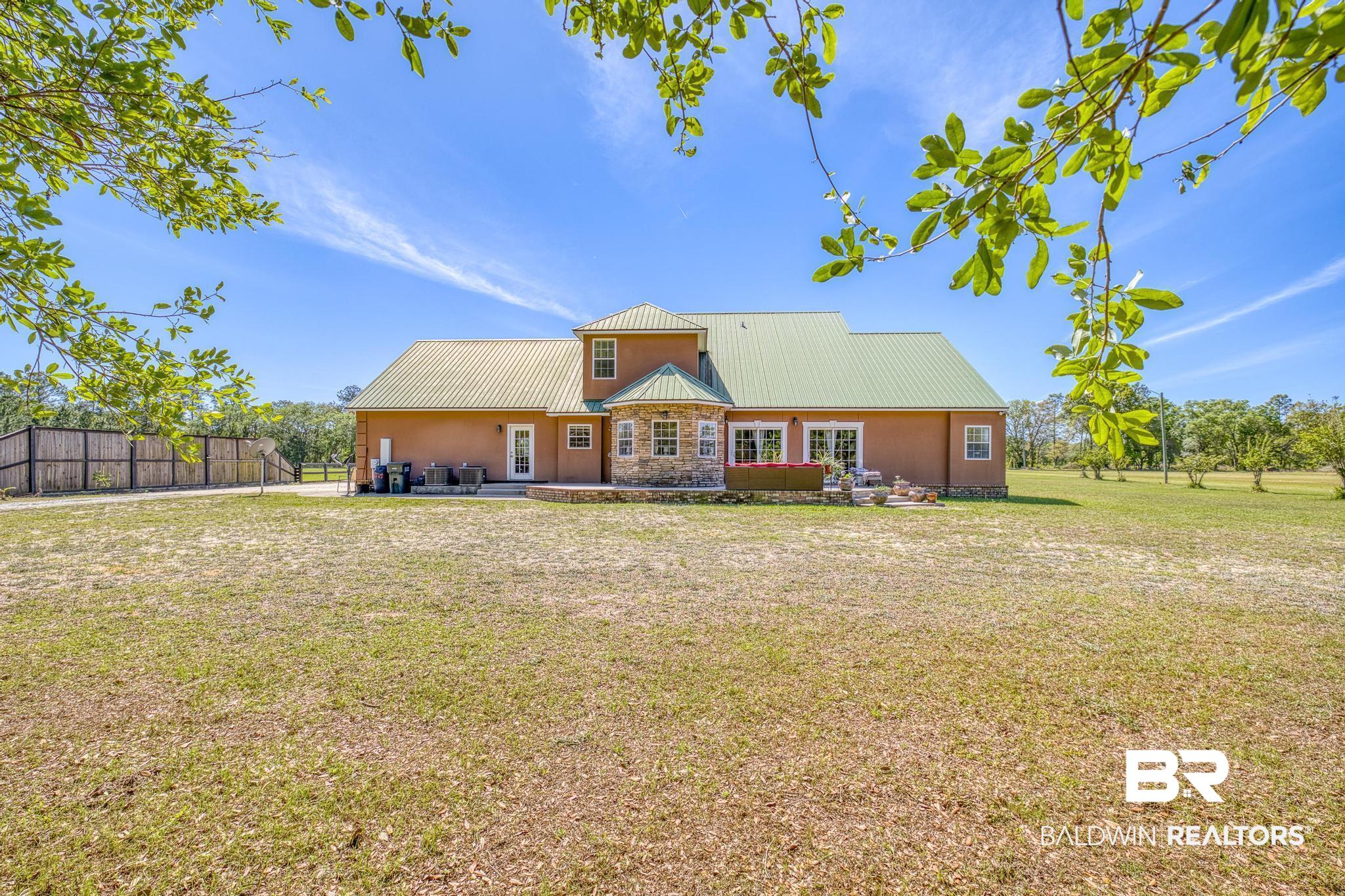 32875 Faircloth Road Lillian, AL 36549 - Photo 68 of 85 Rear view of house featuring a metal roof, a patio, stone siding, and stucco siding