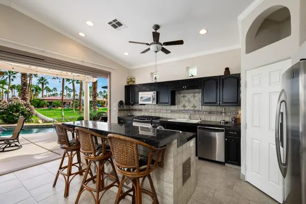 a kitchen with stainless steel appliances granite countertop a stove a refrigerator a sink a stove and white cabinets with wooden floor
