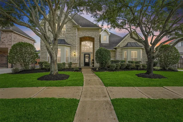 a front view of a house with a garden and trees