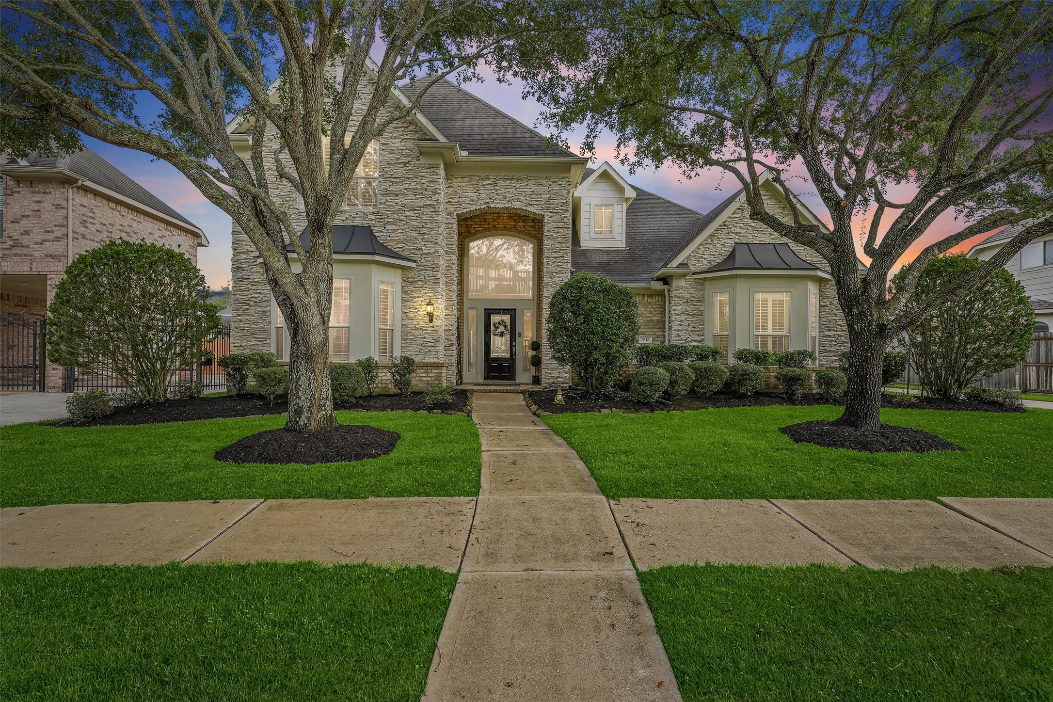 a front view of a house with a garden and trees
