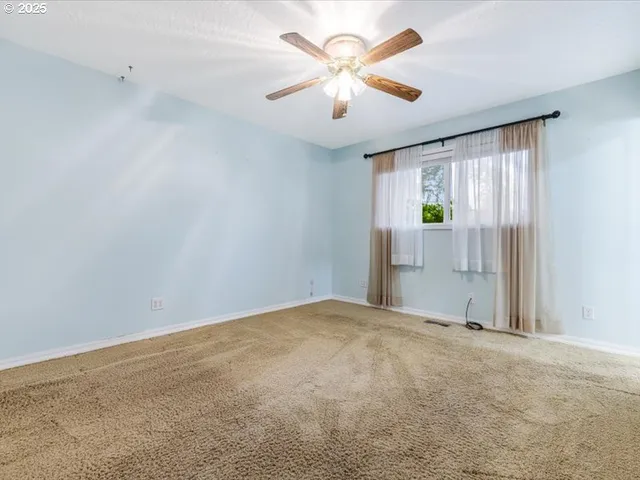 an empty room with windows and fan