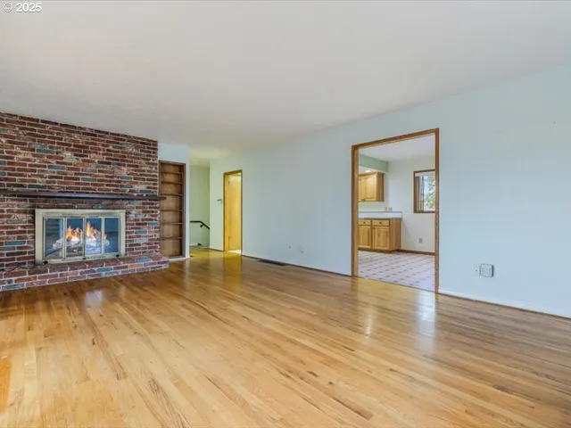 a view of empty room with wooden floor and fireplace