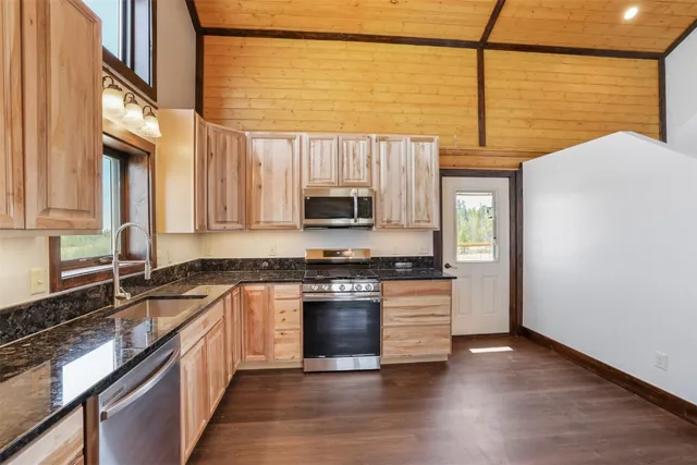 a kitchen with stainless steel appliances granite countertop a stove a sink and a microwave
