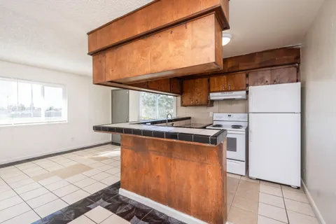 a kitchen with stainless steel appliances granite countertop a refrigerator a stove and a sink with wooden cabinets