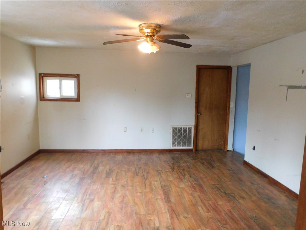 6244 North Ridge Road West Geneva, OH 44041 - Photo 8 of 15 Living room view A featuring a textured ceiling, wood finished floors, visible vents, and baseboards