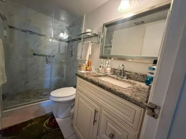 a bathroom with a granite countertop sink toilet and shower