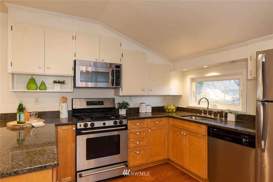 708 North 63rd Street Seattle, WA 98103 - Photo 8 of 24 a kitchen with stainless steel appliances a stove a sink a counter space and cabinets