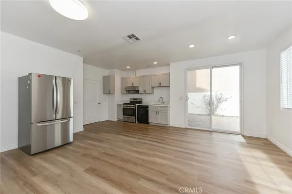 a kitchen with stainless steel appliances wooden floor and window
