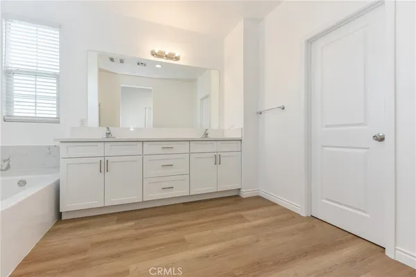 a view of a double vanity sink a mirror a lamp and bathtub