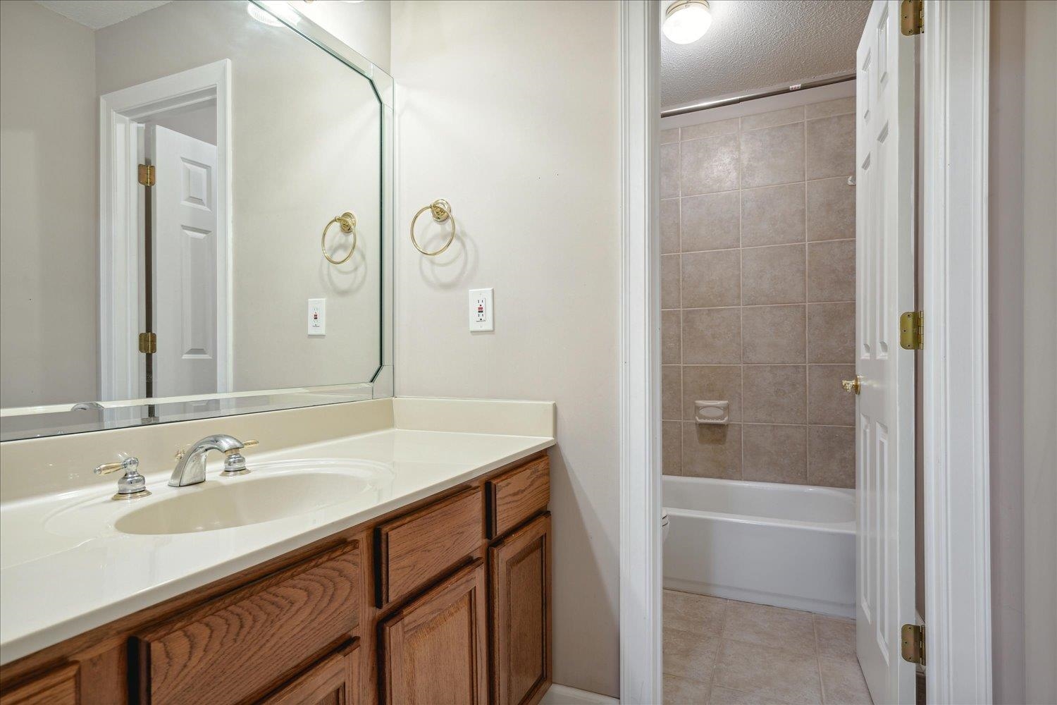 8450 Thor Road Memphis, TN 38018 - Photo 25 of 32 Bathroom featuring a textured ceiling, vanity, tiled shower / bath, and tile patterned flooring