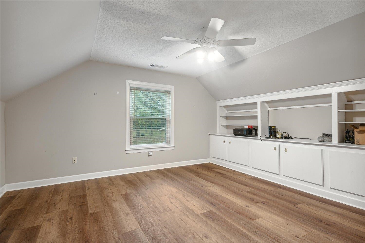8450 Thor Road Memphis, TN 38018 - Photo 27 of 32 Additional living space with built in shelves, a textured ceiling, light hardwood / wood-style flooring, and lofted ceiling
