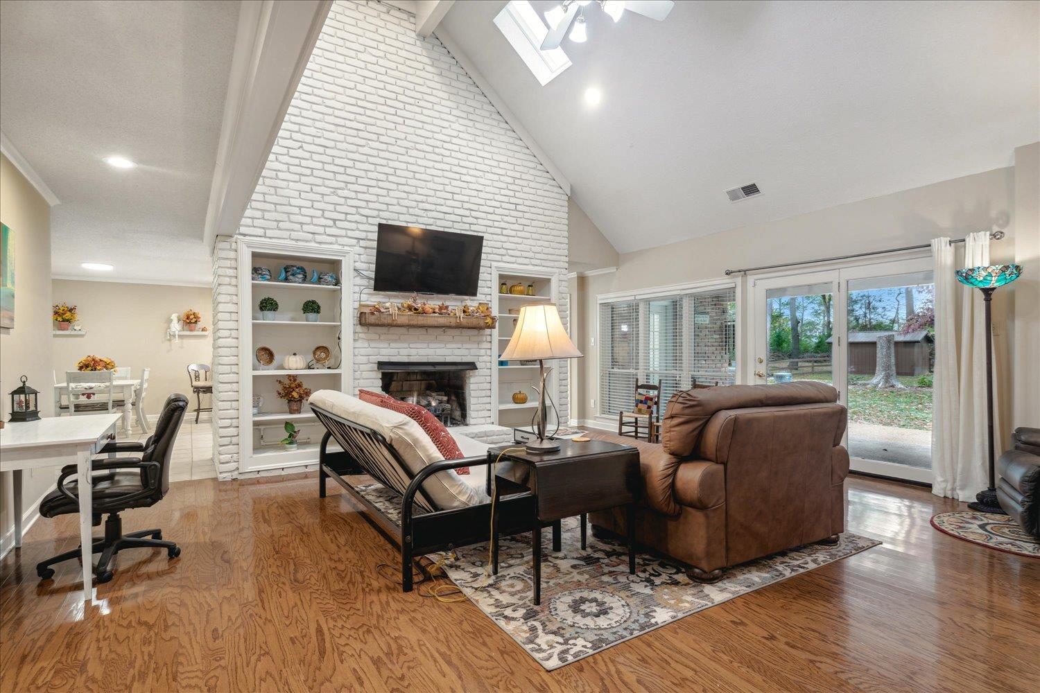 8450 Thor Road Memphis, TN 38018 - Photo 9 of 32 Living room with a skylight, a brick fireplace, high vaulted ceiling, beamed ceiling, and hardwood / wood-style floors