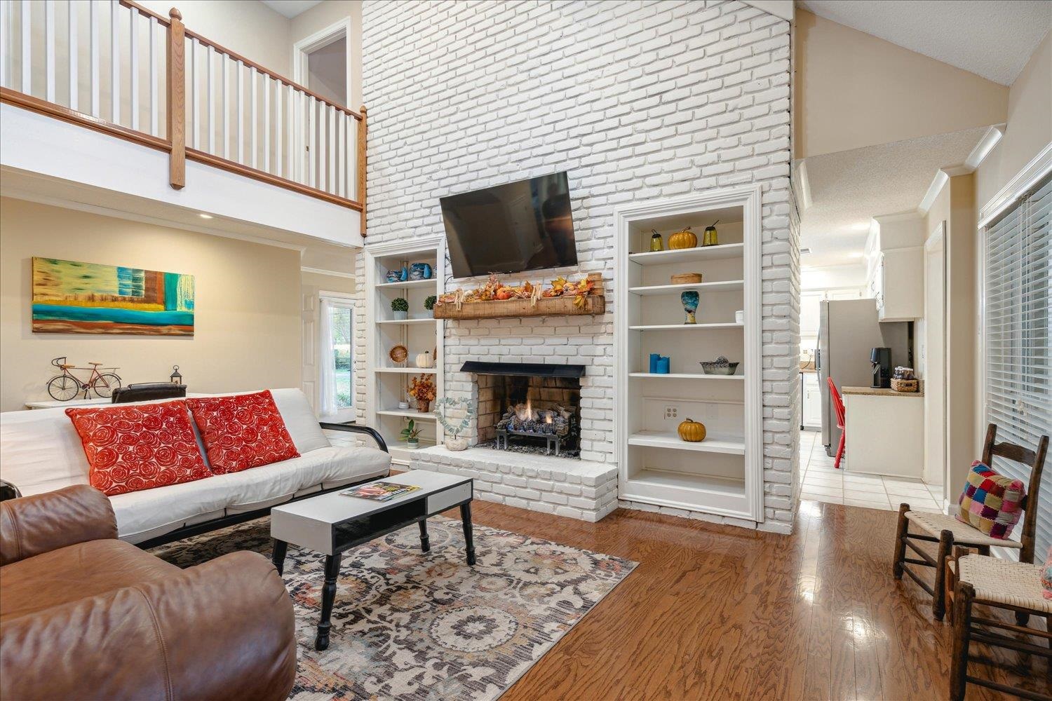 8450 Thor Road Memphis, TN 38018 - Photo 10 of 32 Living room with a brick fireplace, built in shelves, high vaulted ceiling, and hardwood / wood-style flooring