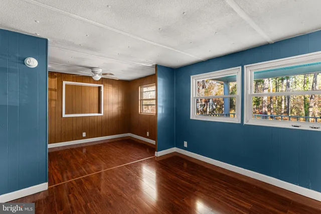 an empty room with wooden floor closet and windows