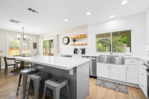 a kitchen with cabinets a sink stainless steel appliances and dining table