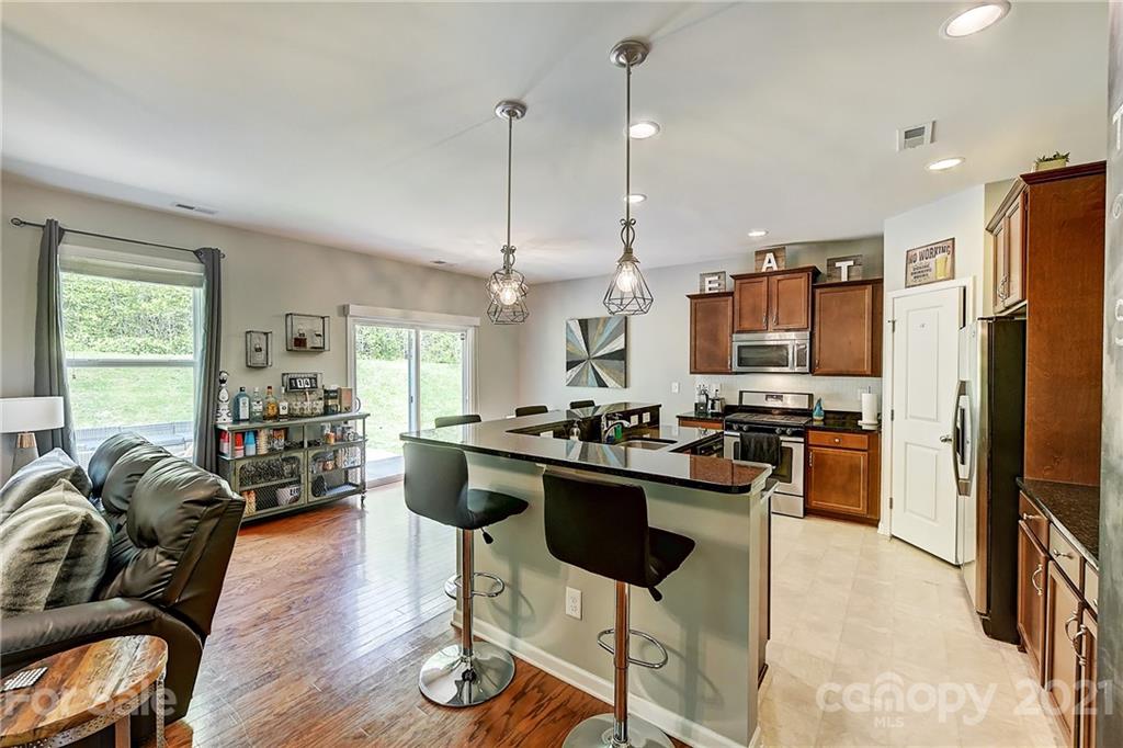 923 Rook Road Charlotte, NC 28216 - Photo 10 of 36 a kitchen with stainless steel appliances kitchen island granite countertop a refrigerator a stove a sink a dining table and chairs with wooden floor