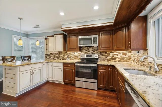 a kitchen with stainless steel appliances granite countertop wooden cabinets a sink and dishwasher a stove top oven with wooden floor