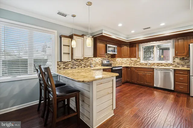 a kitchen with a stove a sink a kitchen island with chairs and wooden floor