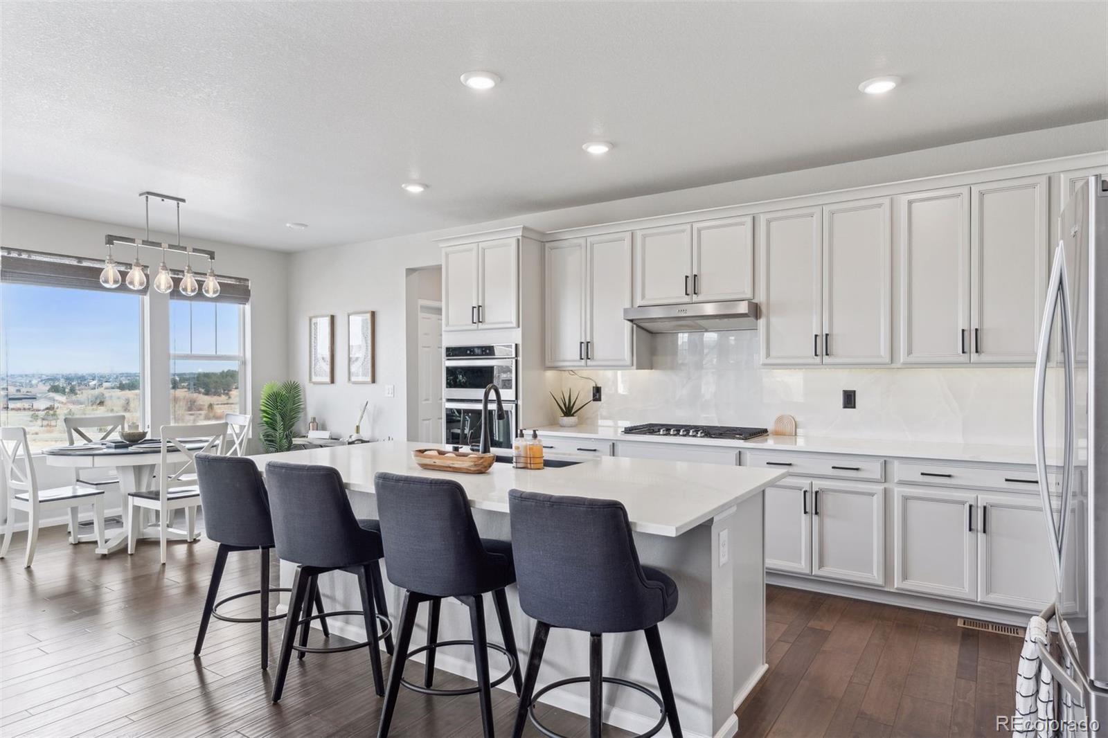 23913 East Minnow Circle Aurora, CO 80016 - Photo 10 of 49 a kitchen with a dining table chairs and white cabinets