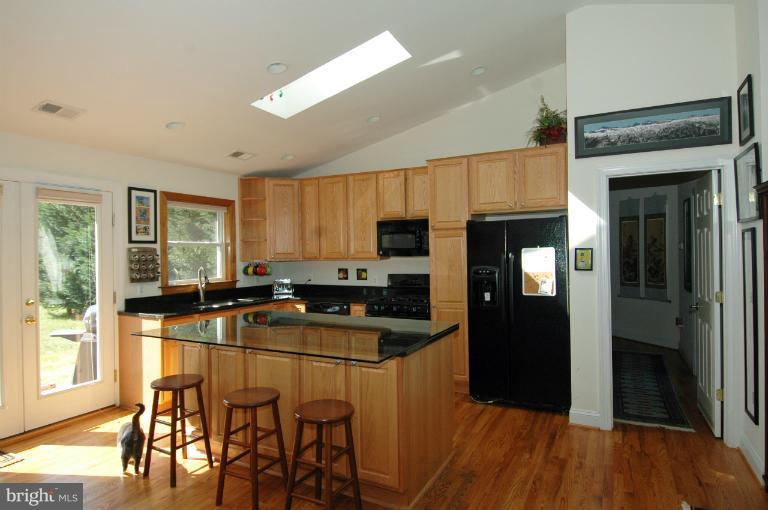 108 Farmington Road West Accokeek, MD 20607 - Photo 9 of 30 a kitchen with stainless steel appliances granite countertop a refrigerator a stove a sink a dining table and chairs with wooden floor