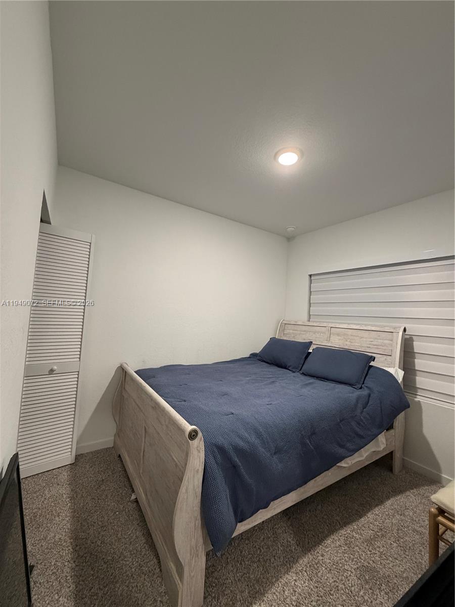 26126 Southwest 146th Avenue, Unit B Homestead, FL 33033 - Photo 3 of 7 a bedroom with a bed and a night stand