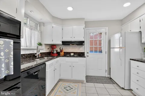 a kitchen with granite countertop a refrigerator stove and sink