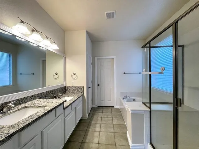 a spacious bathroom with a granite countertop sink a mirror and a shower