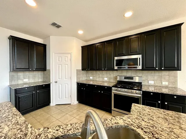a kitchen with stainless steel appliances granite countertop a sink stove and microwave