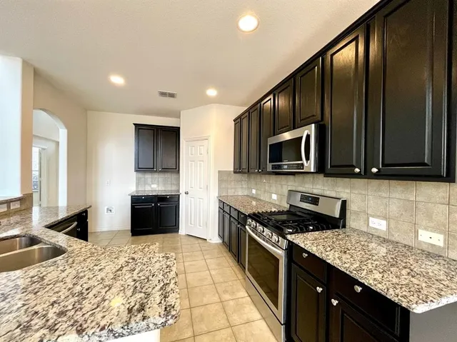a kitchen with stainless steel appliances granite countertop a stove refrigerator and microwave