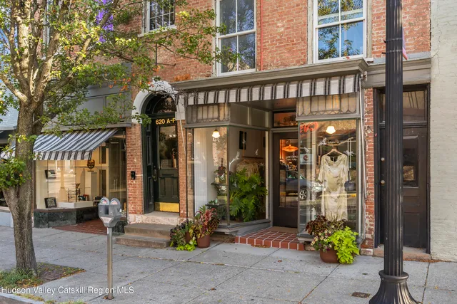 a front view of a building with outdoor seating and a potted plant