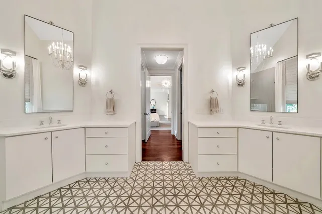 a large white kitchen with granite countertop a stove a sink a dining table and chairs with wooden floor