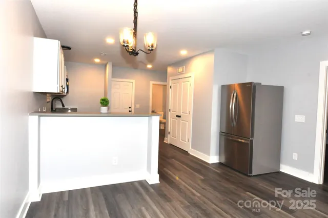 a view of a kitchen with a refrigerator a sink and wooden floor