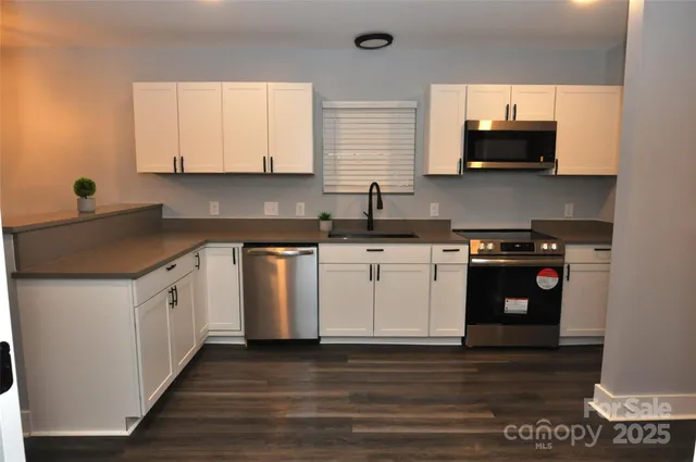 a white kitchen with stainless steel appliances granite countertop a sink and a stove