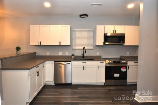 a kitchen with stainless steel appliances granite countertop a stove a sink and a microwave