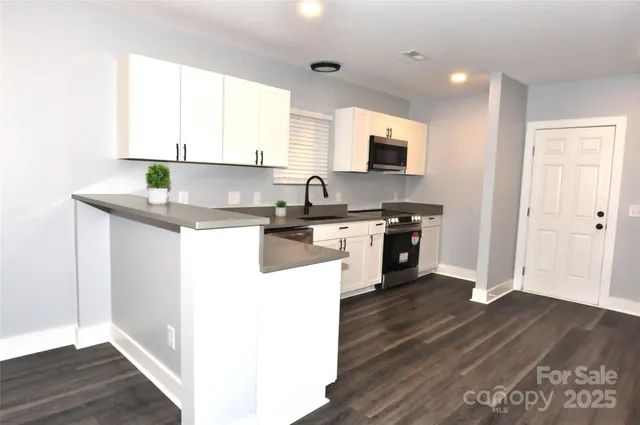 a kitchen with stainless steel appliances granite countertop a sink a stove and cabinets