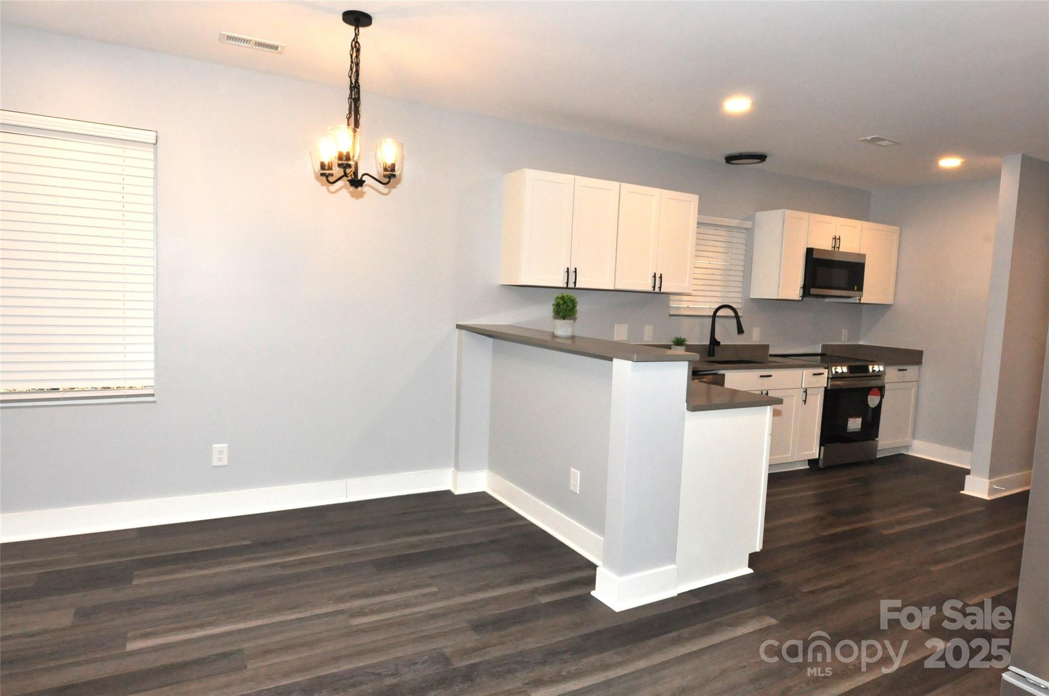 560 2nd Street, Unit 16 Chester, SC 29706 - Photo 10 of 25 a kitchen with stainless steel appliances granite countertop a stove top oven a sink and white cabinets with wooden floor