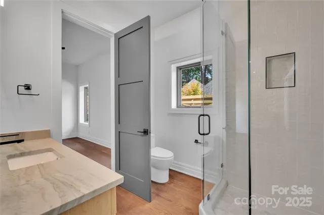 a bathroom with a granite countertop sink a toilet and shower