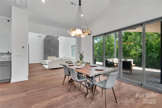 a dining room with wooden floor a chandelier a glass table and chairs